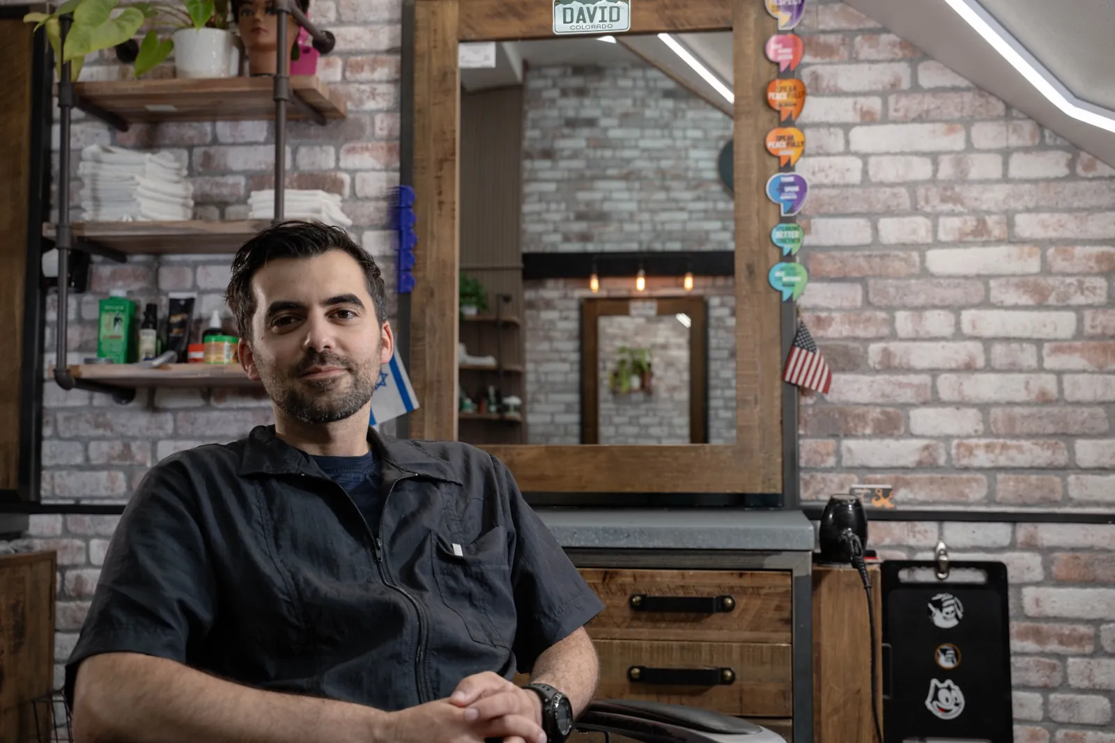David at his barber station inside Alfani's Barbershop Denver with brick walls and hex lighting