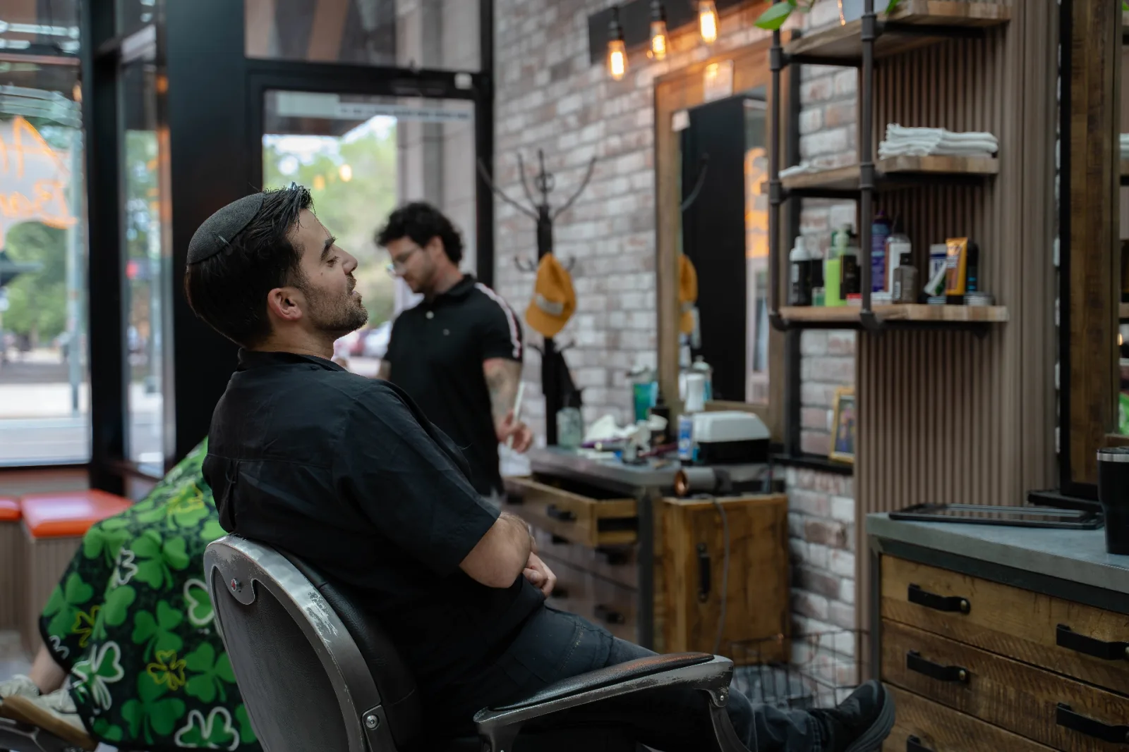 Client relaxing in the chair while Lucca prepares clippers at Alfani's Barbershop Denver