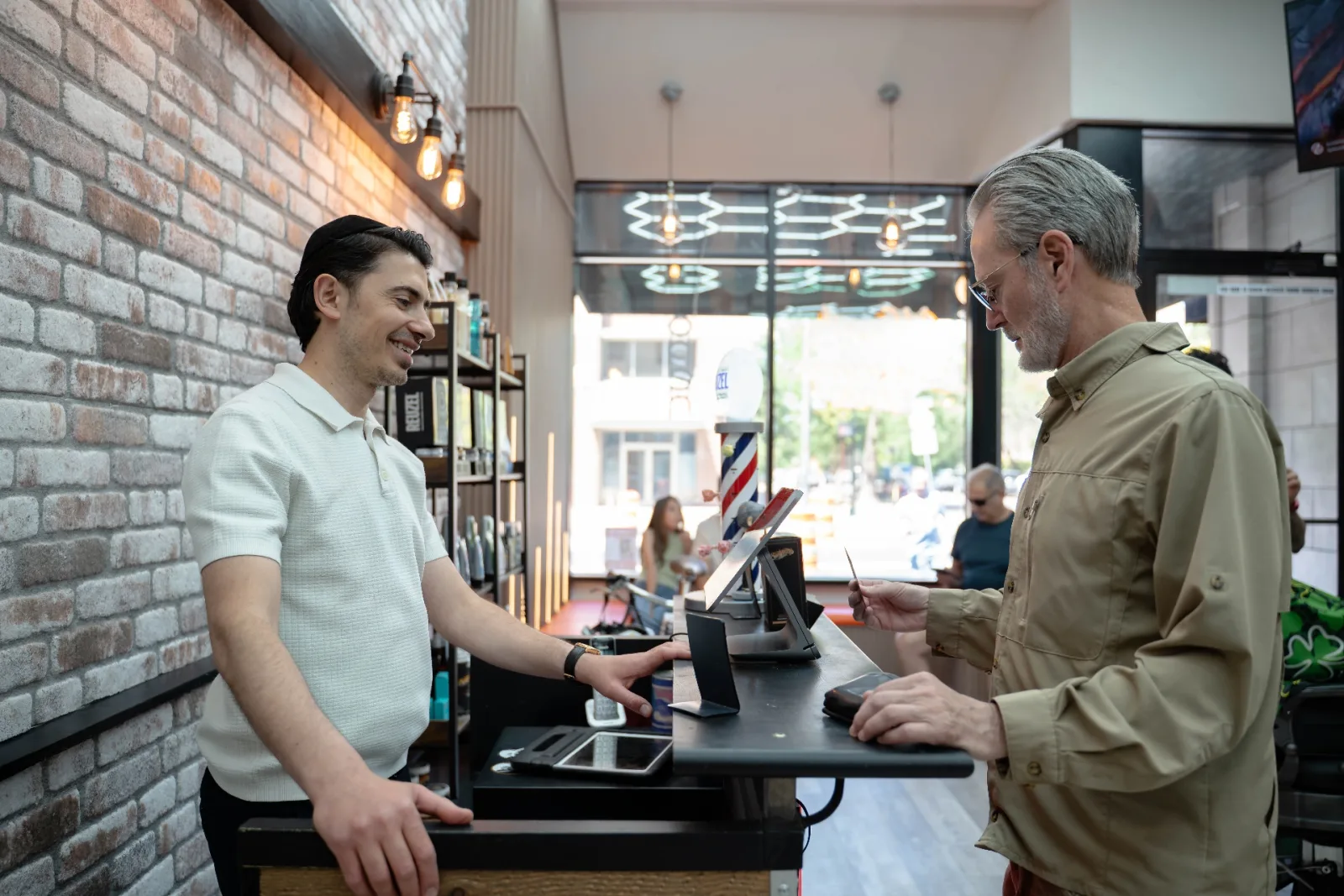 Abo checking out a client at the front counter of Alfani's Barbershop Denver