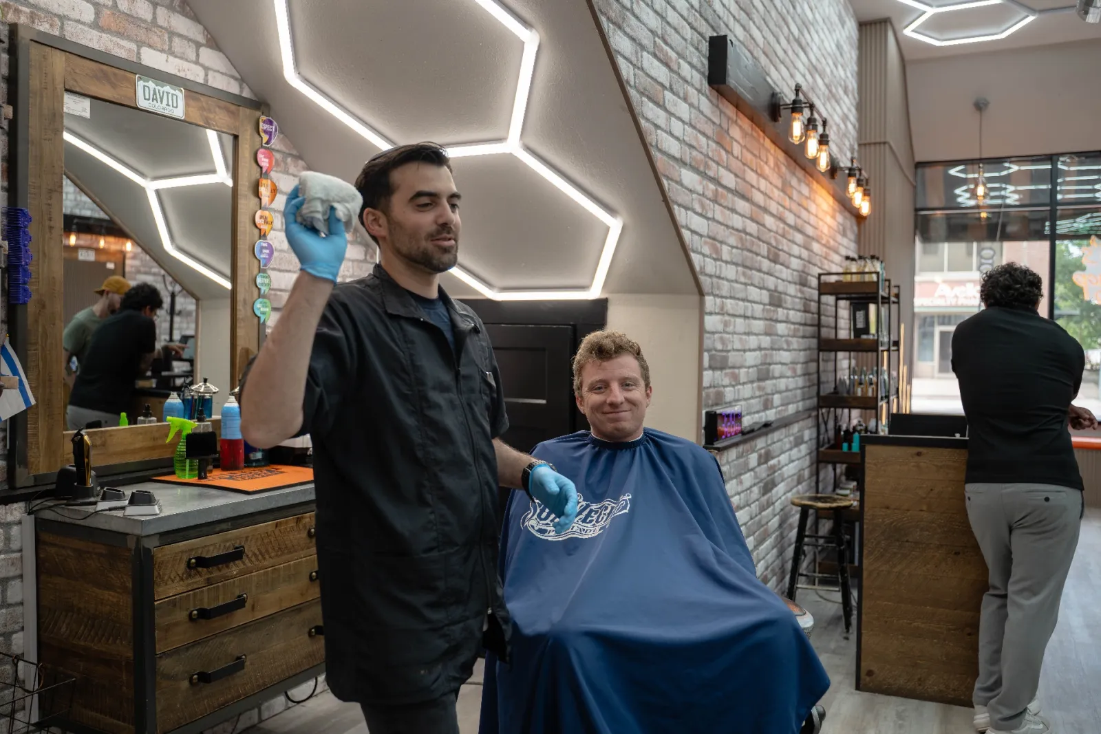 Denver barber David finishing a haircut on a happy client at Alfani's Barbershop on East Colfax