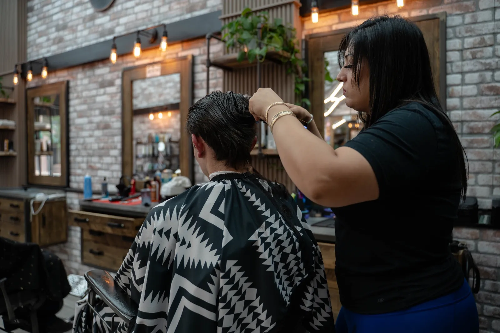 Maria doing a scissor-over-comb men's haircut at Alfani's Barbershop Denver